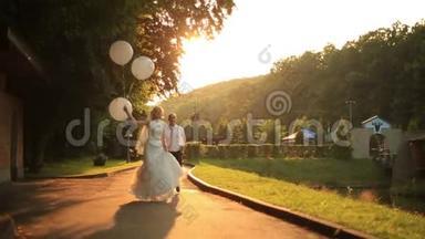 快<strong>乐</strong>的新婚夫妇在夕阳下的<strong>金秋</strong>公园里拿着气球散步，一起玩得开心